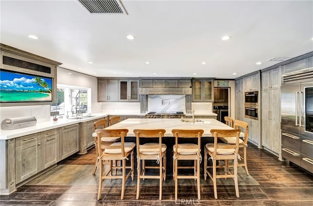 5441 Calvin Ave, Tarzana, CA 91356 - kitchen featuring glass insert cabinets, light countertops, a kitchen island with sink, visible vents, and a sink