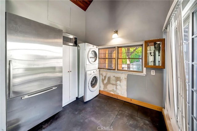 5441 Calvin Ave, Tarzana, CA 91356 - laundry room featuring laundry area, stacked washer and dryer, baseboards, and a towering ceiling