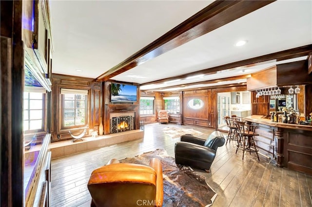 5441 Calvin Ave, Tarzana, CA 91356 - living room featuring bar, a warm lit fireplace, wooden walls, beam ceiling, and hardwood / wood-style flooring
