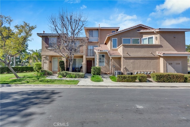 multi unit property featuring central AC unit, stucco siding, a tiled roof, and a front lawn