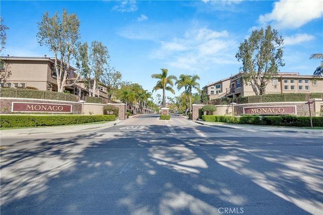 view of road with a gated entry, a residential view, curbs, and sidewalks