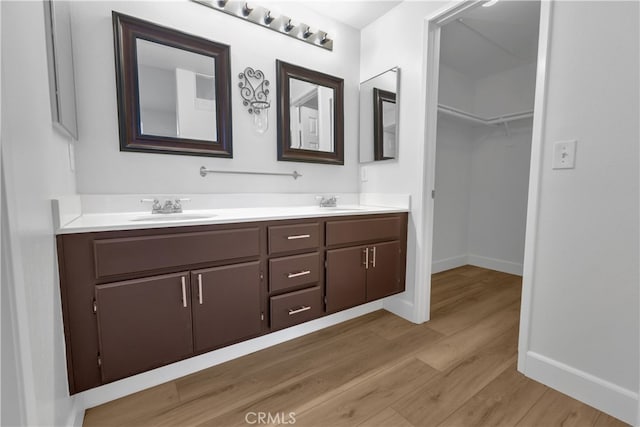 full bathroom with double vanity, wood finished floors, baseboards, and a sink