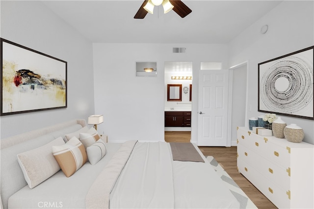 bedroom with ceiling fan, visible vents, wood finished floors, and ensuite bathroom