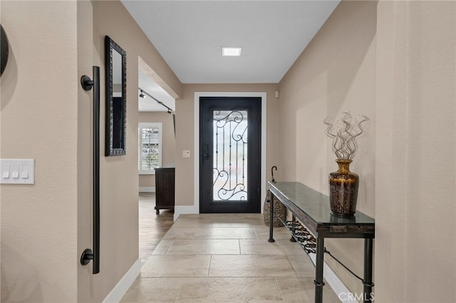 foyer featuring baseboards and stone tile floors