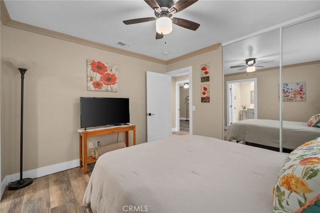 bedroom with wood finished floors, baseboards, visible vents, ceiling fan, and ornamental molding