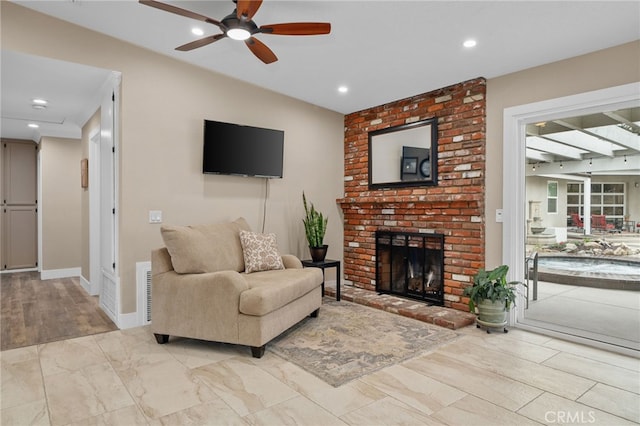 living room with recessed lighting, baseboards, a brick fireplace, and ceiling fan