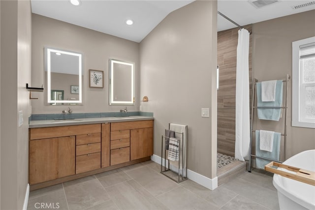 full bathroom with double vanity, tiled shower, visible vents, and a sink