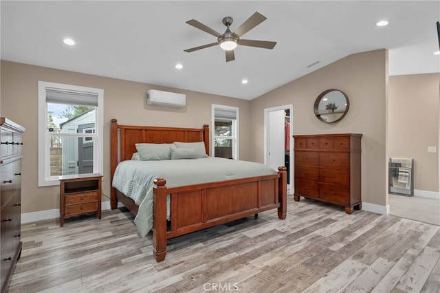 bedroom with a wall mounted air conditioner, heating unit, light wood-style flooring, and vaulted ceiling