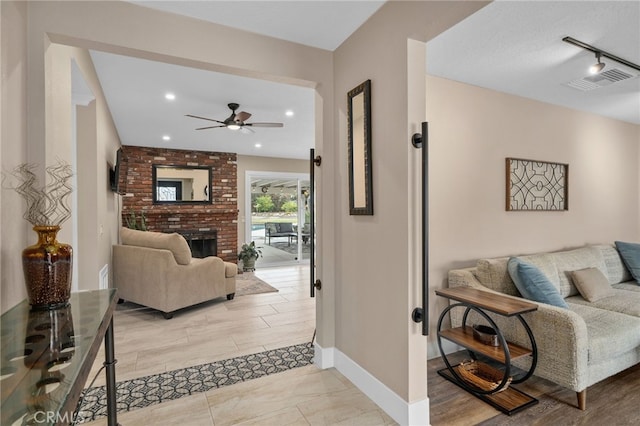 living room featuring baseboards, visible vents, recessed lighting, rail lighting, and a brick fireplace