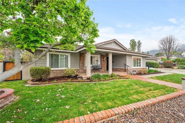 view of front of house with brick siding, a front lawn, and fence