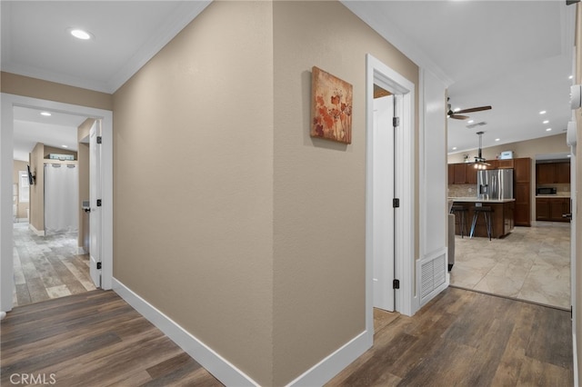 hall featuring visible vents, wood finished floors, and baseboards