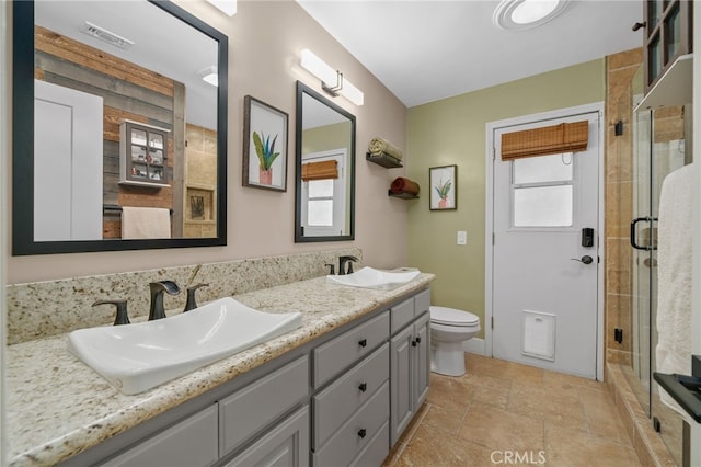 bathroom with plenty of natural light, a shower stall, toilet, and a sink