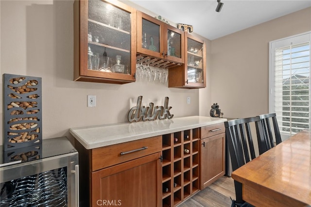 bar with wine cooler and light wood finished floors