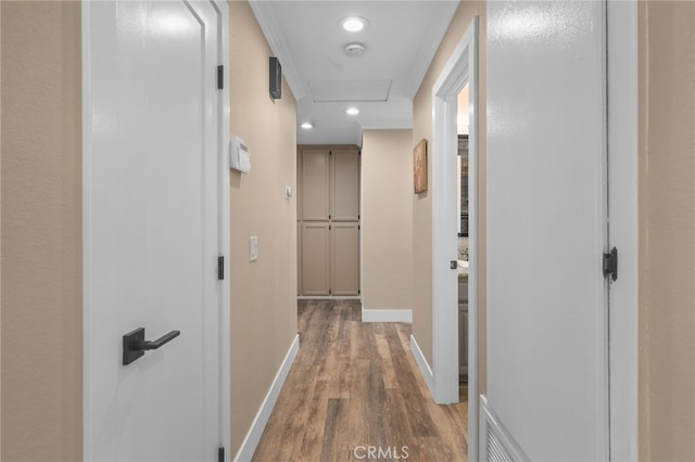 corridor with recessed lighting, baseboards, attic access, and wood finished floors