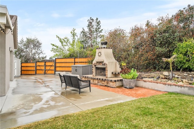 view of patio featuring a gate, exterior fireplace, and fence