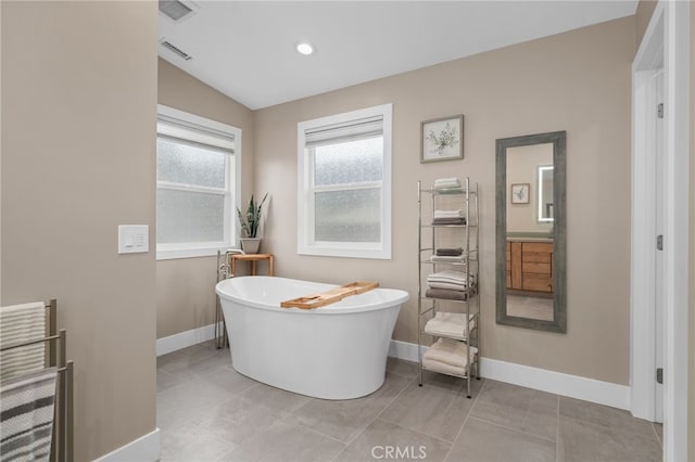 bathroom featuring visible vents, radiator, tile patterned flooring, baseboards, and a freestanding bath