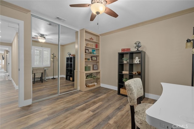 office space with visible vents, crown molding, baseboards, and wood finished floors