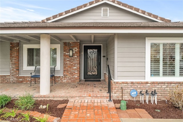 property entrance featuring brick siding and a porch