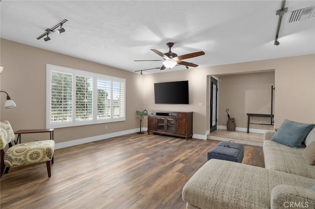 living room with visible vents, baseboards, rail lighting, wood finished floors, and a ceiling fan