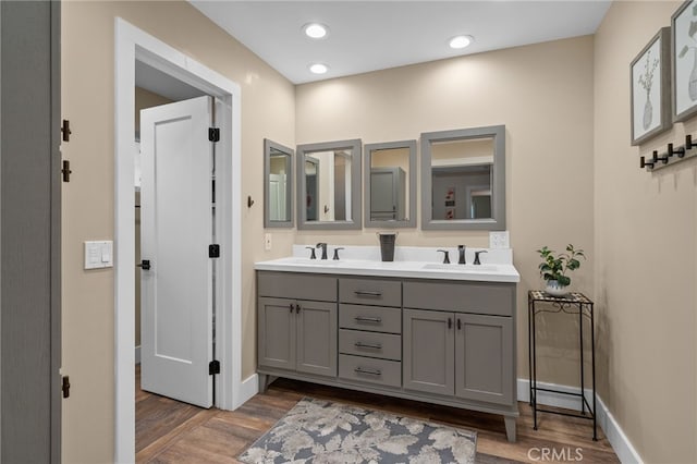 full bath with double vanity, wood finished floors, and a sink