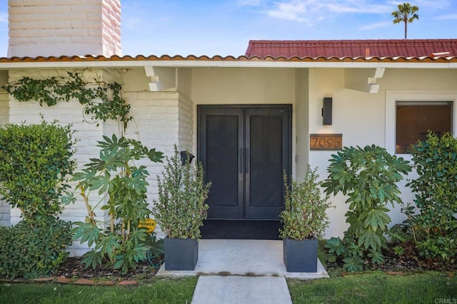 entrance to property with stucco siding and a tiled roof