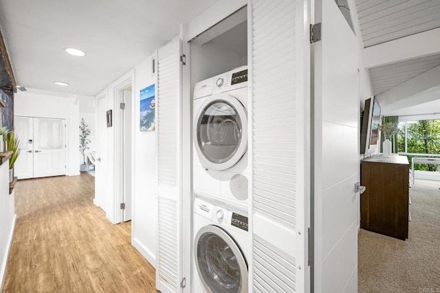 washroom featuring stacked washer / drying machine, laundry area, and light wood finished floors