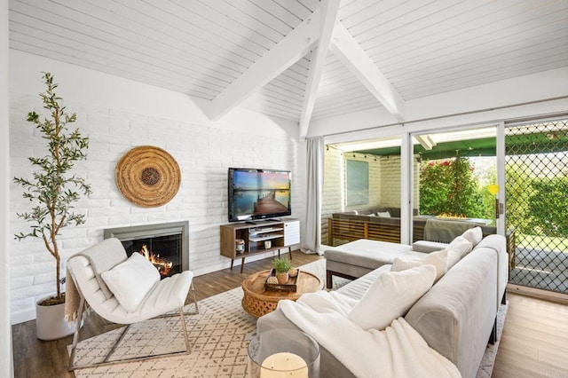 living area with a fireplace, lofted ceiling with beams, and wood finished floors