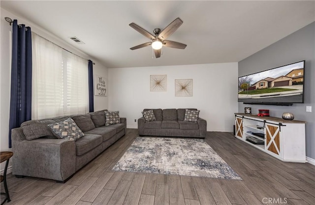 living area with ceiling fan, visible vents, baseboards, and wood finished floors