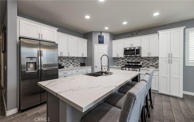 kitchen featuring a sink, stainless steel appliances, wood tiled floor, and white cabinetry