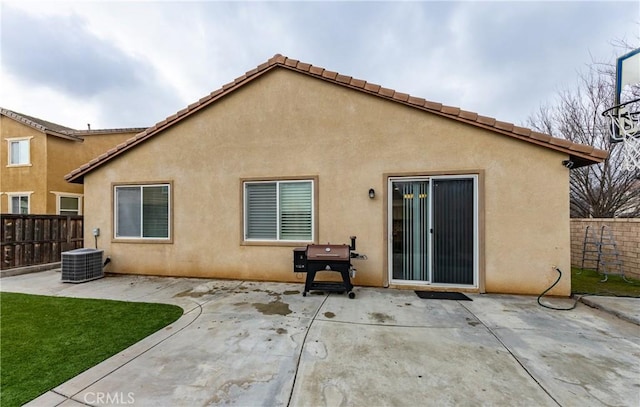 rear view of house featuring fence, stucco siding, cooling unit, a lawn, and a patio area