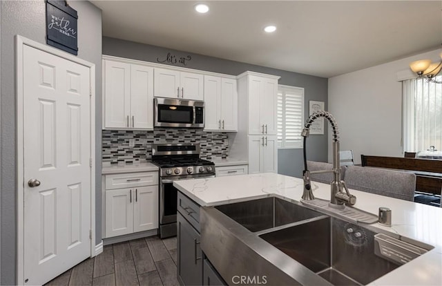 kitchen with dark wood-style floors, a sink, decorative backsplash, stainless steel appliances, and white cabinetry