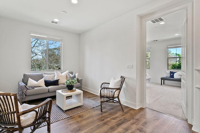 living area with wood finished floors, visible vents, and baseboards