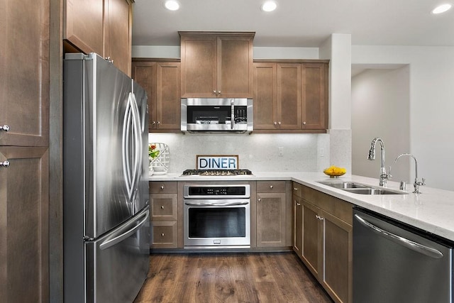 kitchen featuring dark wood-type flooring, a sink, recessed lighting, appliances with stainless steel finishes, and decorative backsplash