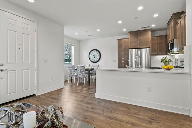 kitchen featuring dark wood-style floors, recessed lighting, stainless steel appliances, a peninsula, and light countertops