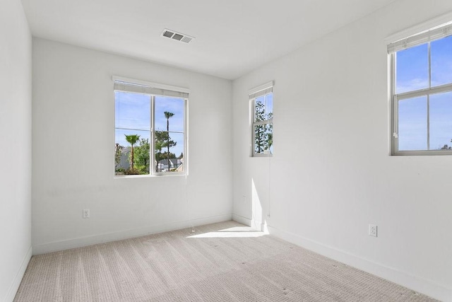 empty room featuring visible vents, a healthy amount of sunlight, and carpet