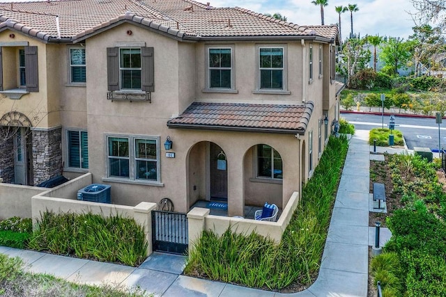 view of front of home with a gate, stucco siding, a fenced front yard, and a tiled roof