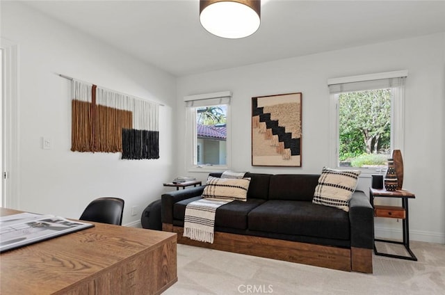 living area featuring light colored carpet, baseboards, and a healthy amount of sunlight