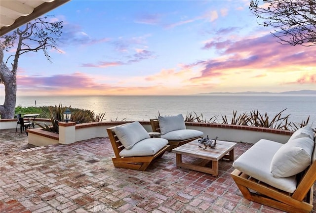 patio terrace at dusk with outdoor lounge area and a water view