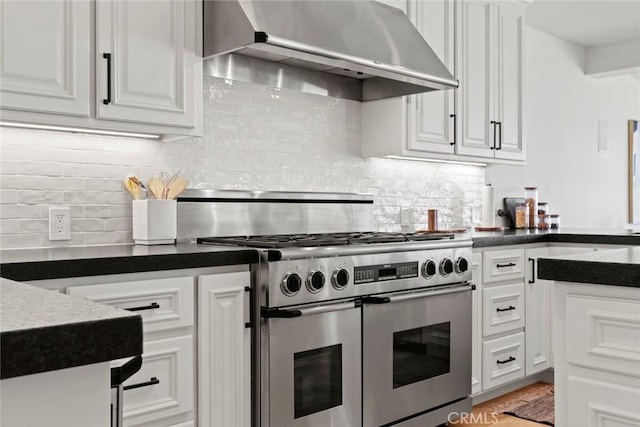 kitchen with under cabinet range hood, white cabinets, dark countertops, and range with two ovens