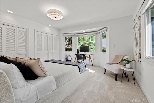 bedroom with recessed lighting, baseboards, two closets, and light carpet