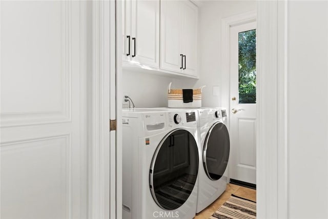 washroom featuring washer and dryer, cabinet space, and light tile patterned floors