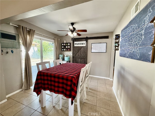 dining space with a barn door, light tile patterned flooring, a ceiling fan, and baseboards