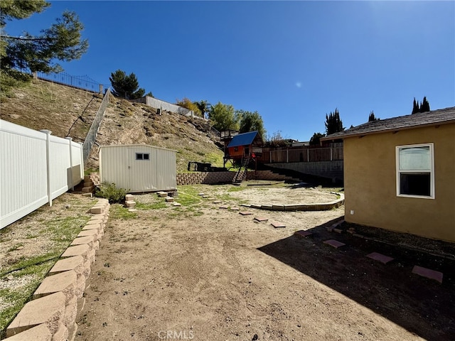 view of yard featuring an outbuilding, a storage unit, and fence