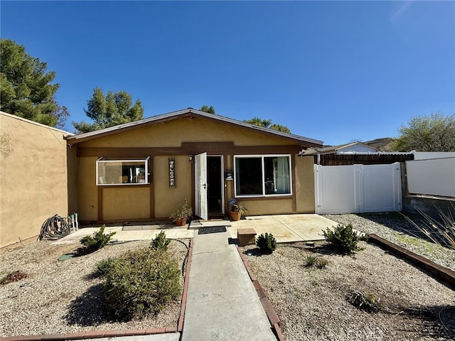 view of front of house with stucco siding, fence, and a gate