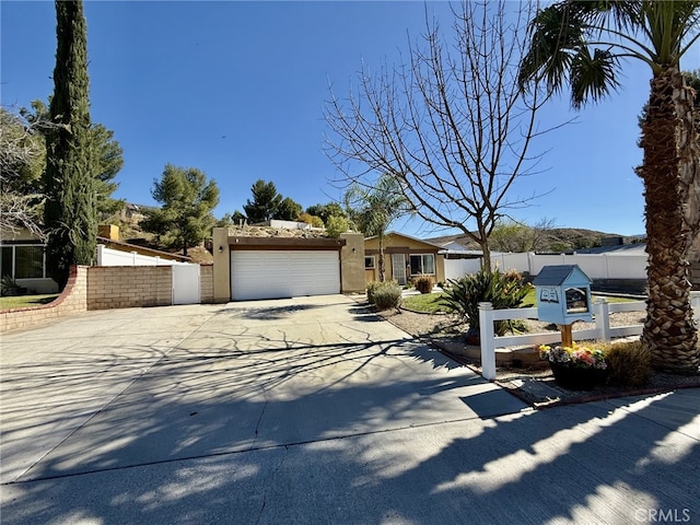 view of front of property with an attached garage, fence, driveway, and stucco siding