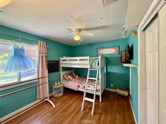 bedroom featuring visible vents, baseboards, a textured ceiling, and wood finished floors