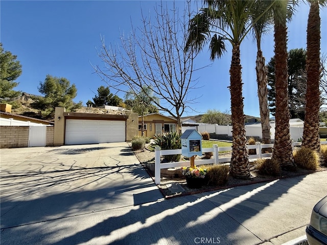 view of front of house with concrete driveway, an attached garage, a fenced front yard, and stucco siding