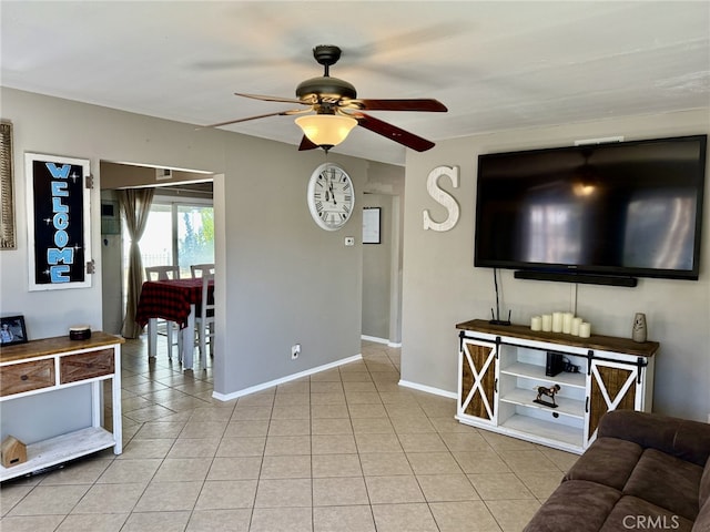 living area featuring light tile patterned flooring, ceiling fan, and baseboards