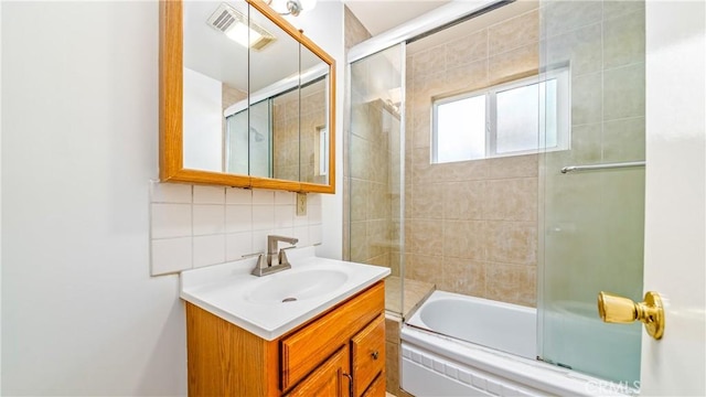 bathroom with vanity, tasteful backsplash, visible vents, and bath / shower combo with glass door