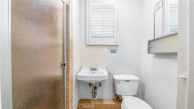 bathroom featuring tile patterned floors, decorative backsplash, toilet, and a stall shower